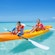 A young boy and girl at sea in a two-person kayak wearing matching life vests and holding paddles